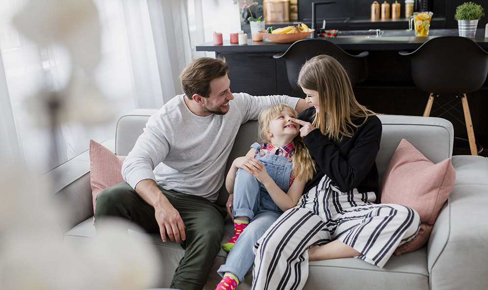 Glückliche Familie auf Sofa in Eigenheim